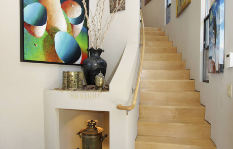 A staircase with art on the wall and a vase