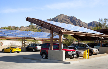 A car park with cars parked under a solar panel.