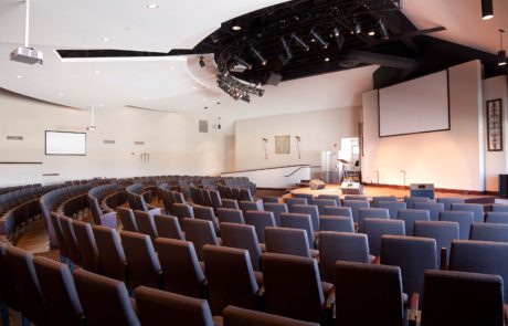 A large auditorium with rows of chairs and a projector.