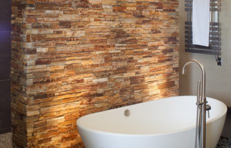 A bathroom with stone walls and a tub.